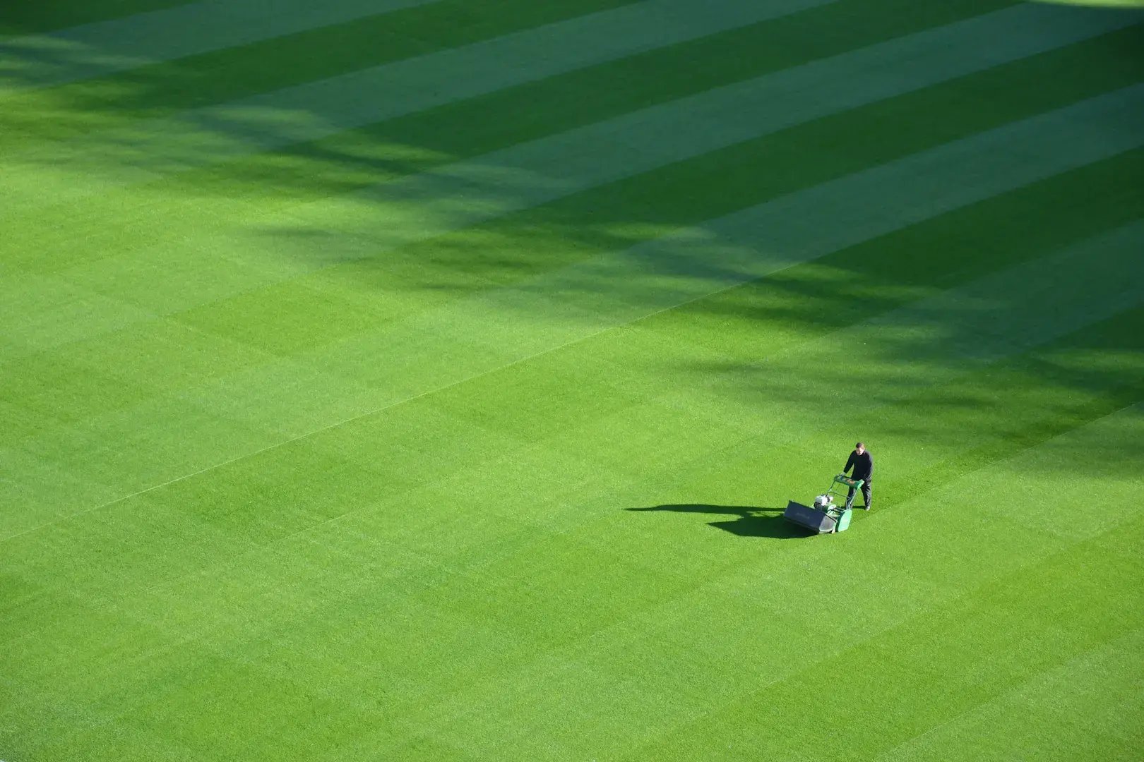 man mowing grass on sports field